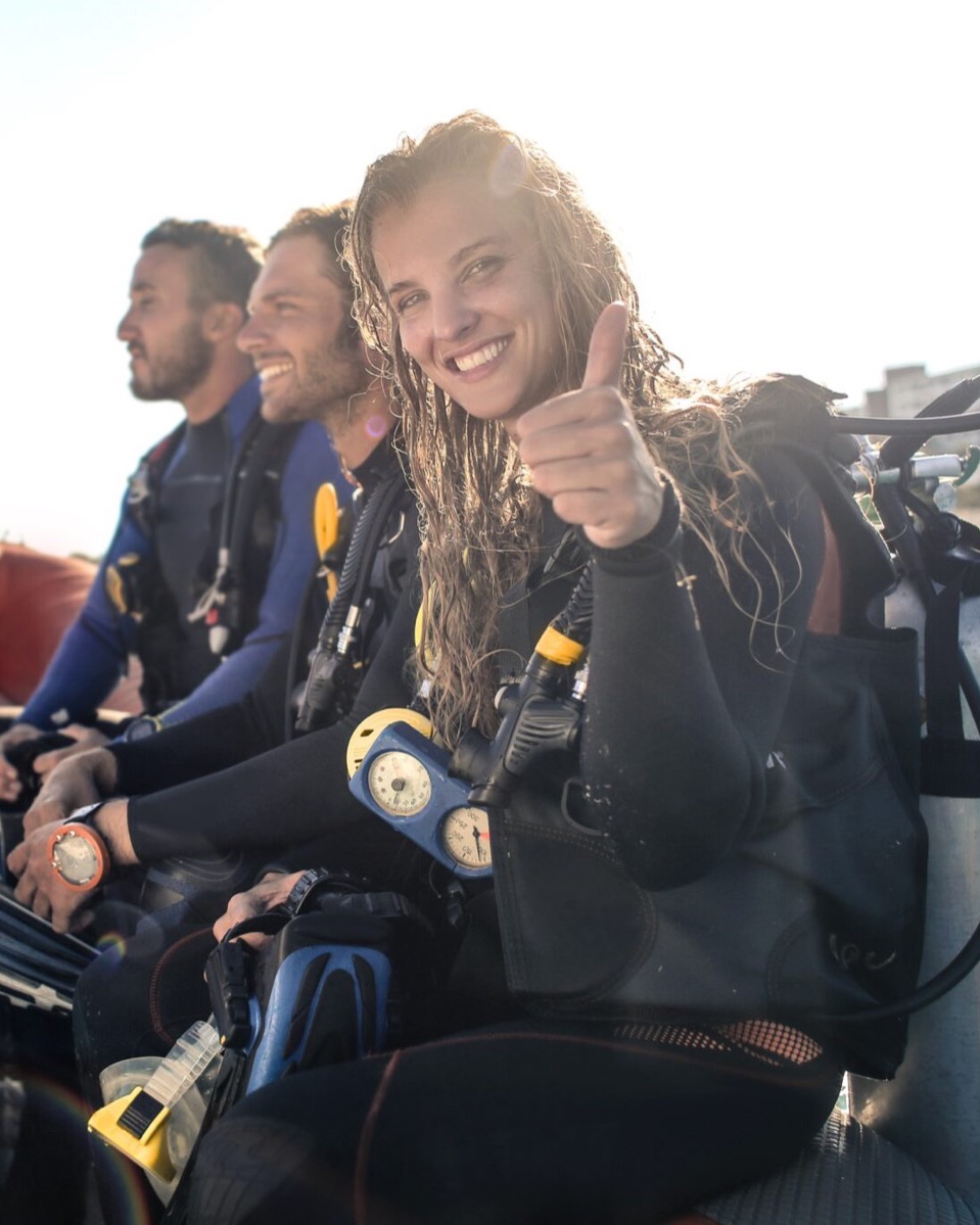 Smiling scuba divers on a dive boat, one giving a thumbs up